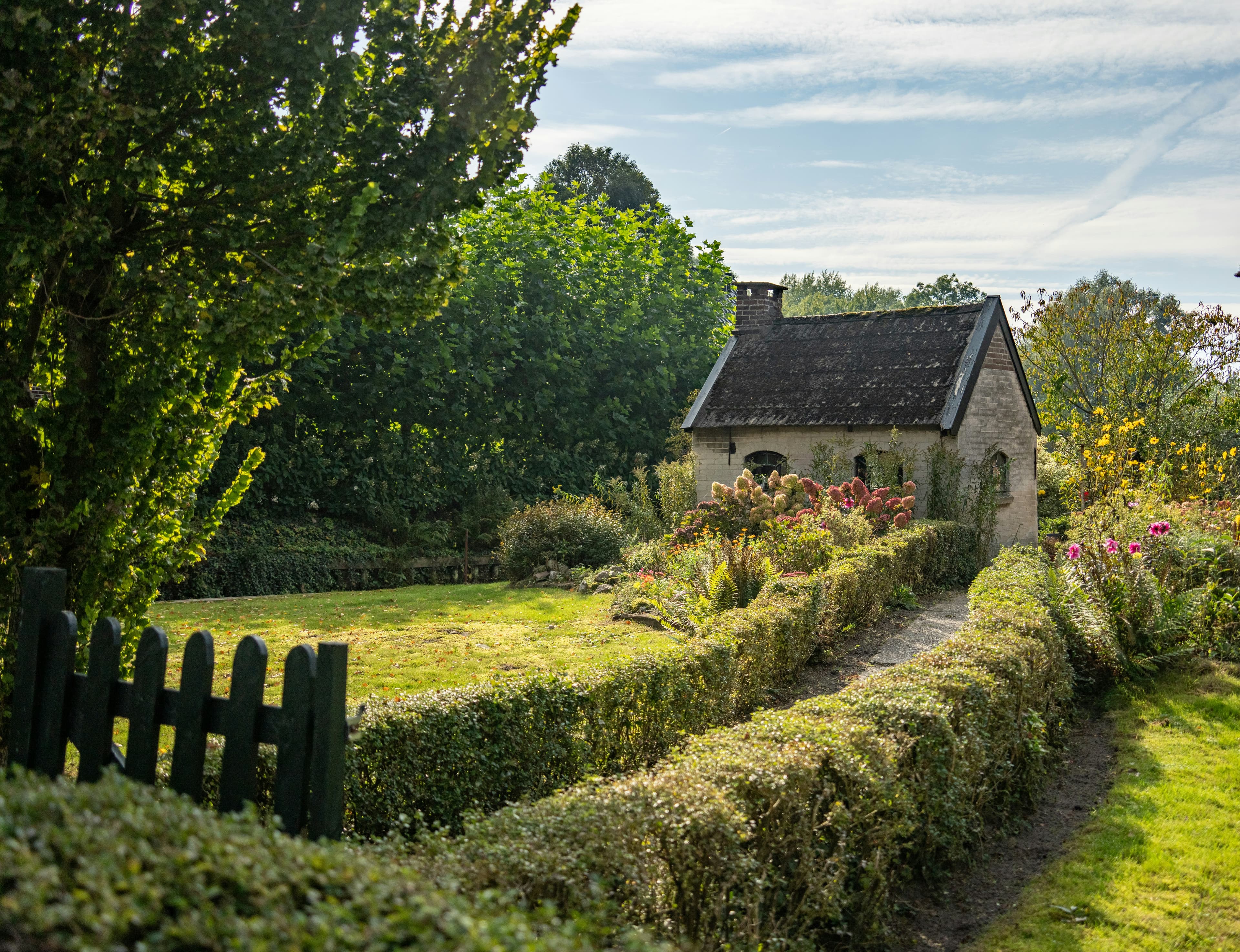 Stone cottage with garden path and hedgerows